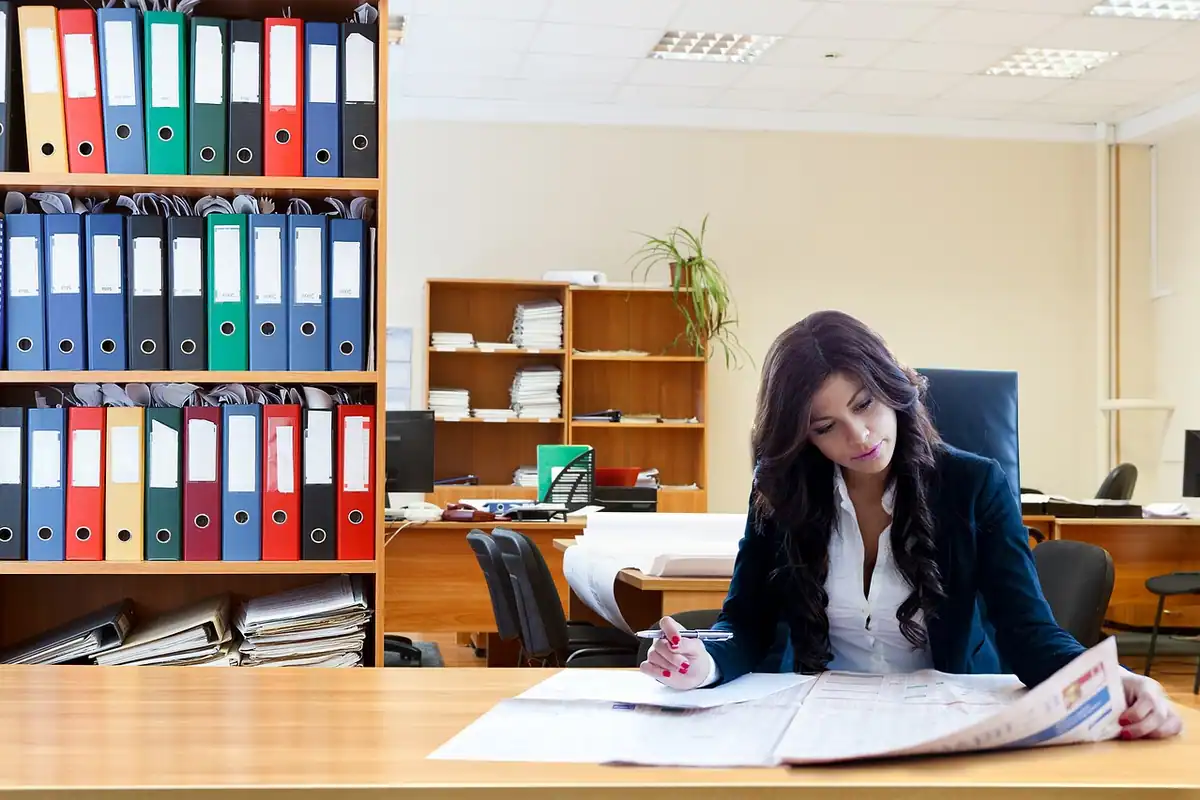 Manager concentrată la birou, între dosare, care analizează un raport despre rezultatele echipei