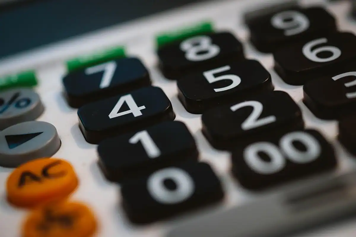 Calculator și foi cu calcule așezate pe un birou, pentru construirea bugetului unui proiect