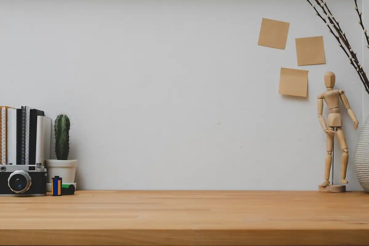 Birou minimalist cu perete de cărămidă, un caiet și o plantă decorativă