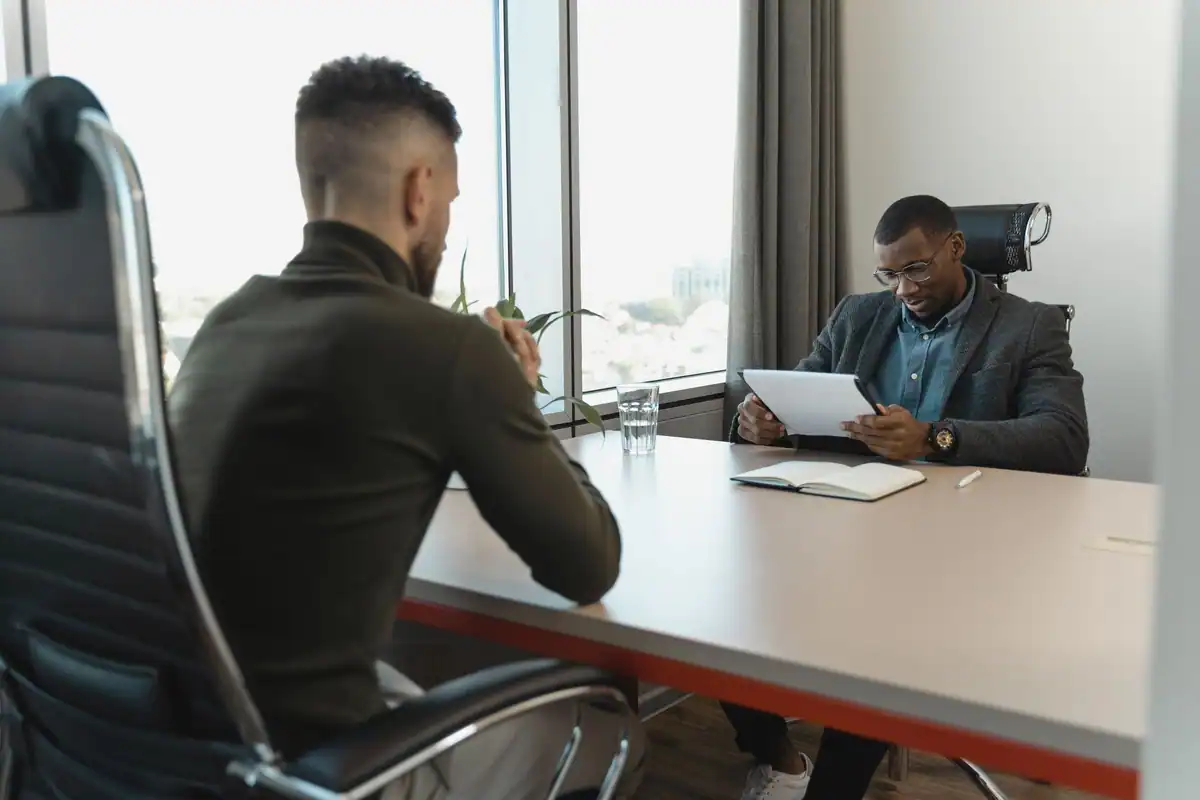 Manager și angajat față în față la un birou, într-o discuție despre feedback