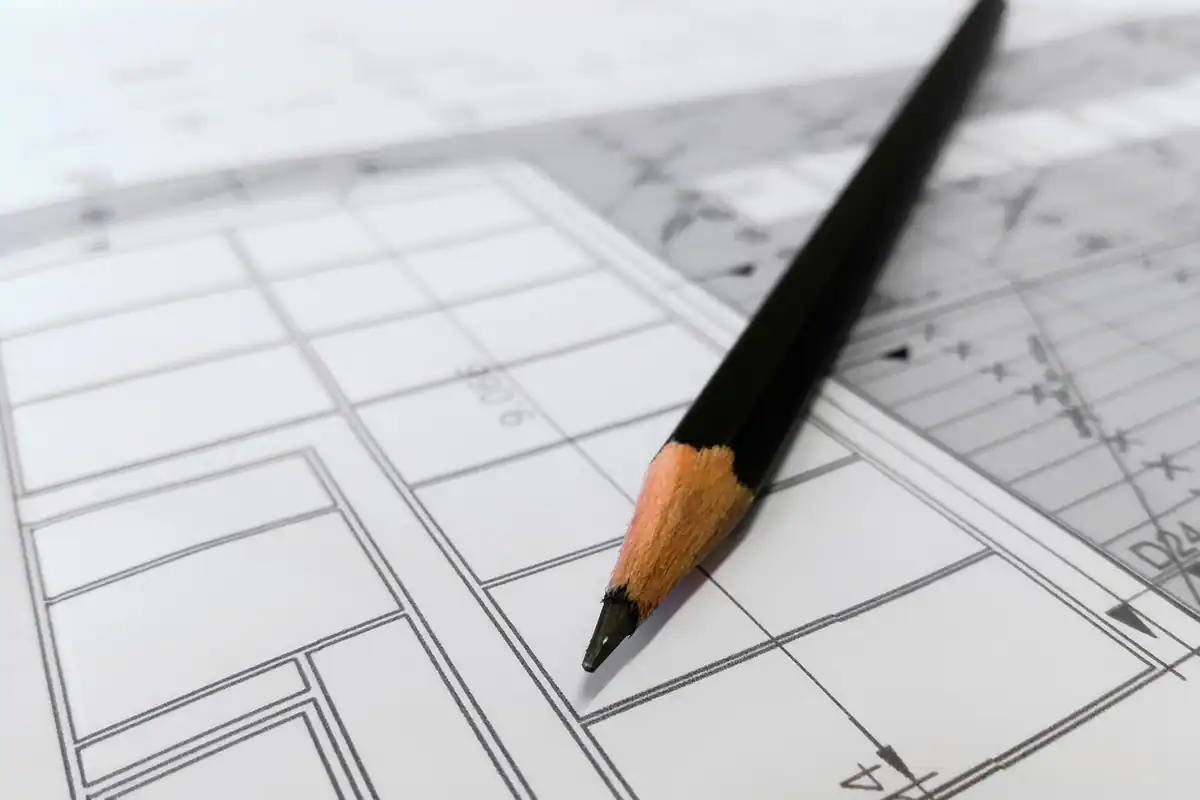 Schiță a planului unui birou desenată pe hârtie, cu un creion alături, pentru împărțirea posturilor