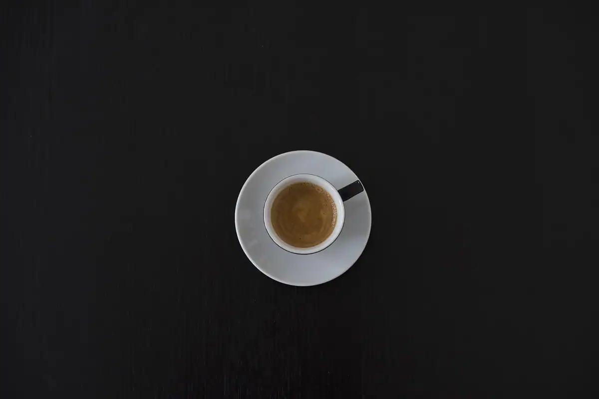 Două căni de cafea văzute de sus, pe o masă de ședință, la o discuție de evaluare