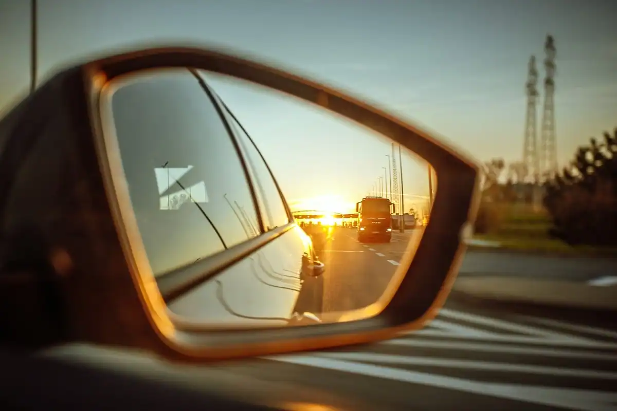 Oglindă laterală de mașină în care se reflectă drumul, simbol al punctelor oarbe ale unui lider